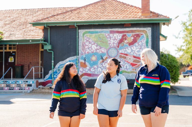 Girls walking in front of Indigenous artwork